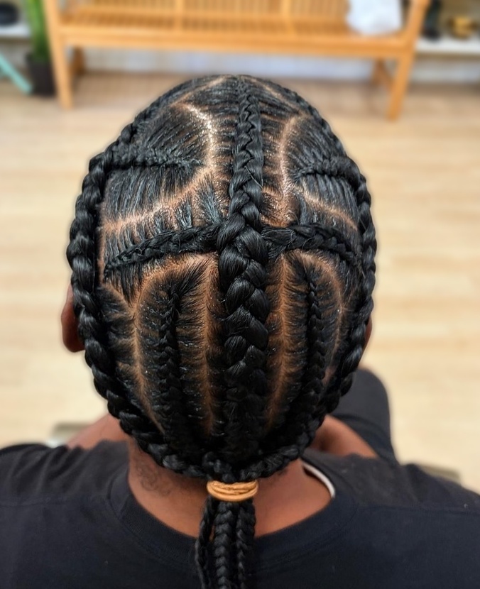 Geometric cornrows gathered into a low braided ponytail at TEXTURES Hair Salon