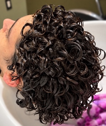 Perm to create defined curls, shown at the shampoo bowl at TEXTURES Hair Salon