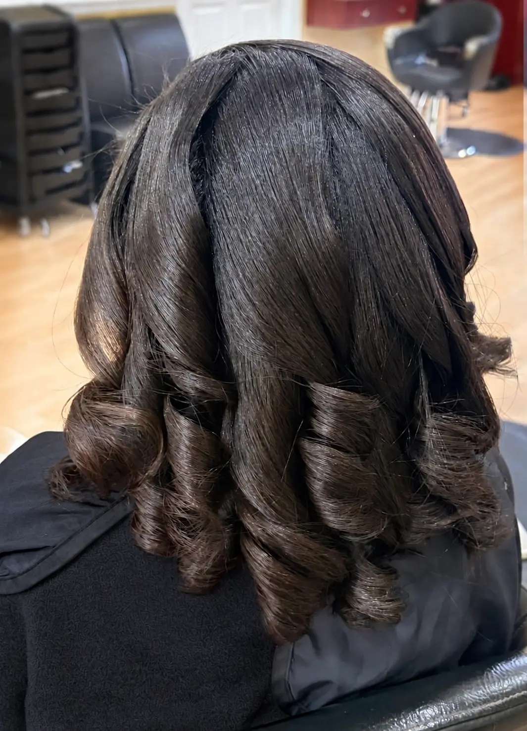 After a press and curl: back view of smooth, glossy hair with defined curls at TEXTURES Hair Salon