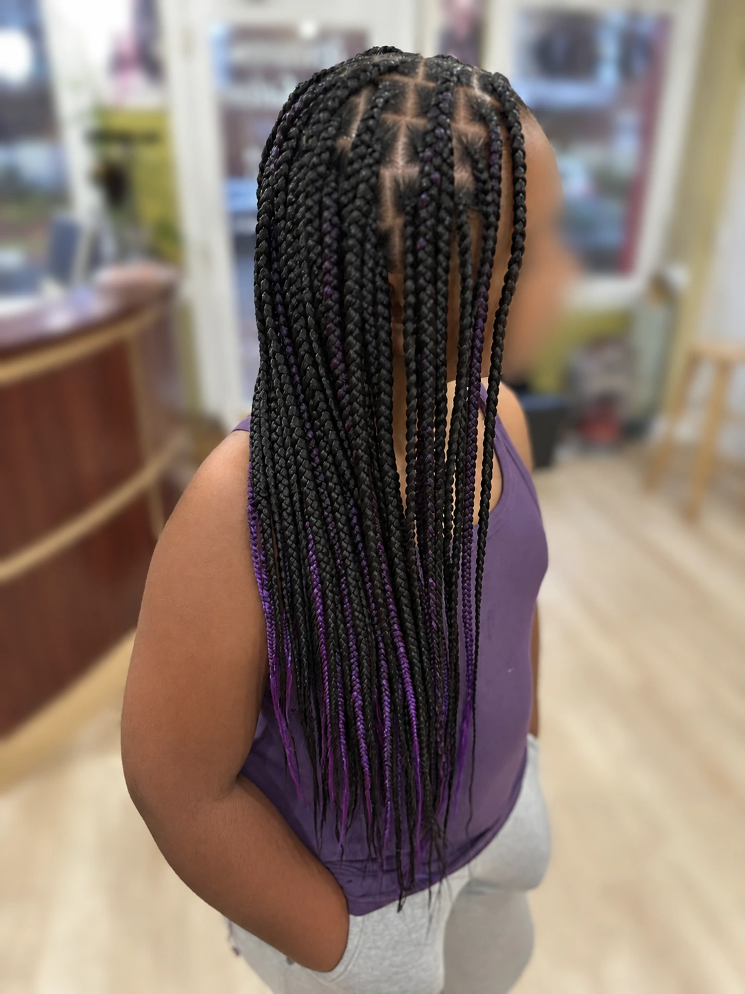 Long individual braids with purple accents at TEXTURES Hair Salon