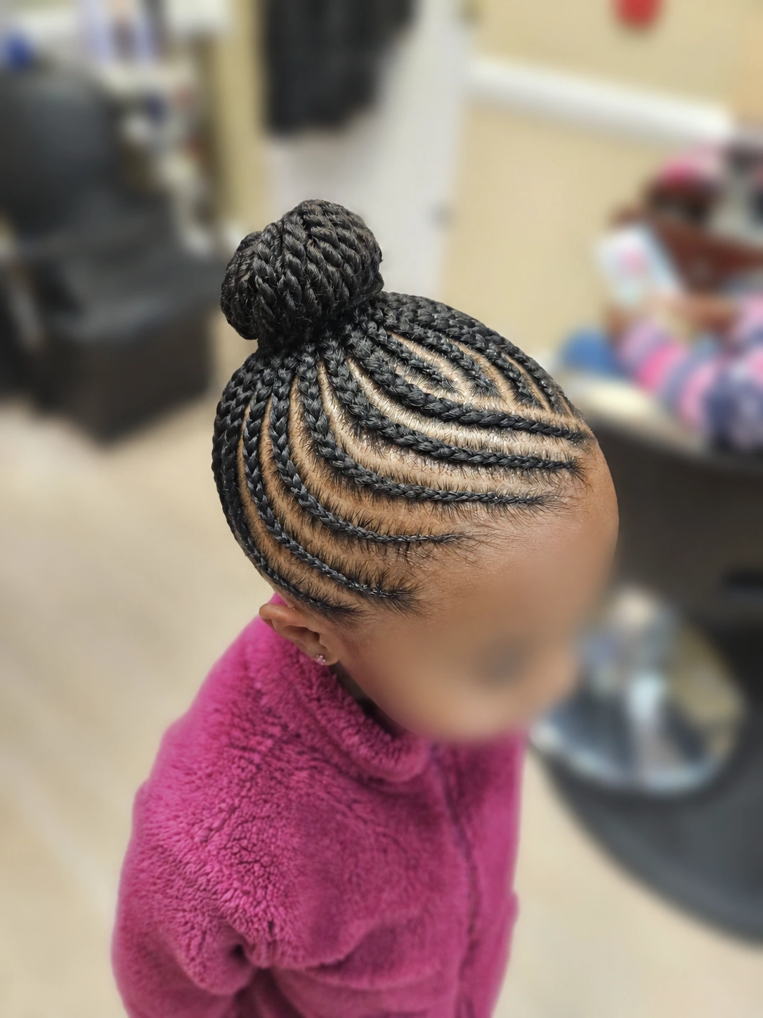 Kids’ cornrows with a high braided bun at TEXTURES Hair Salon
