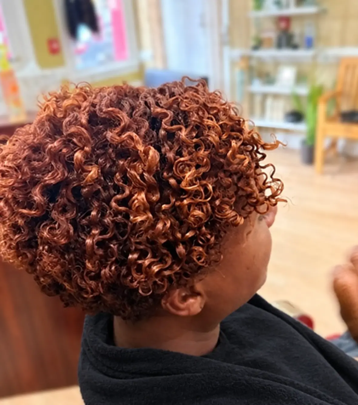 Short copper-toned defined curls at TEXTURES Hair Salon