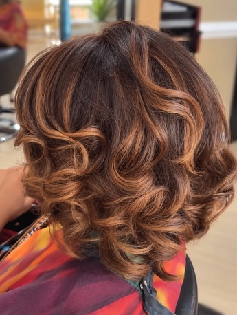 Layered curls with warm highlights at TEXTURES Hair Salon