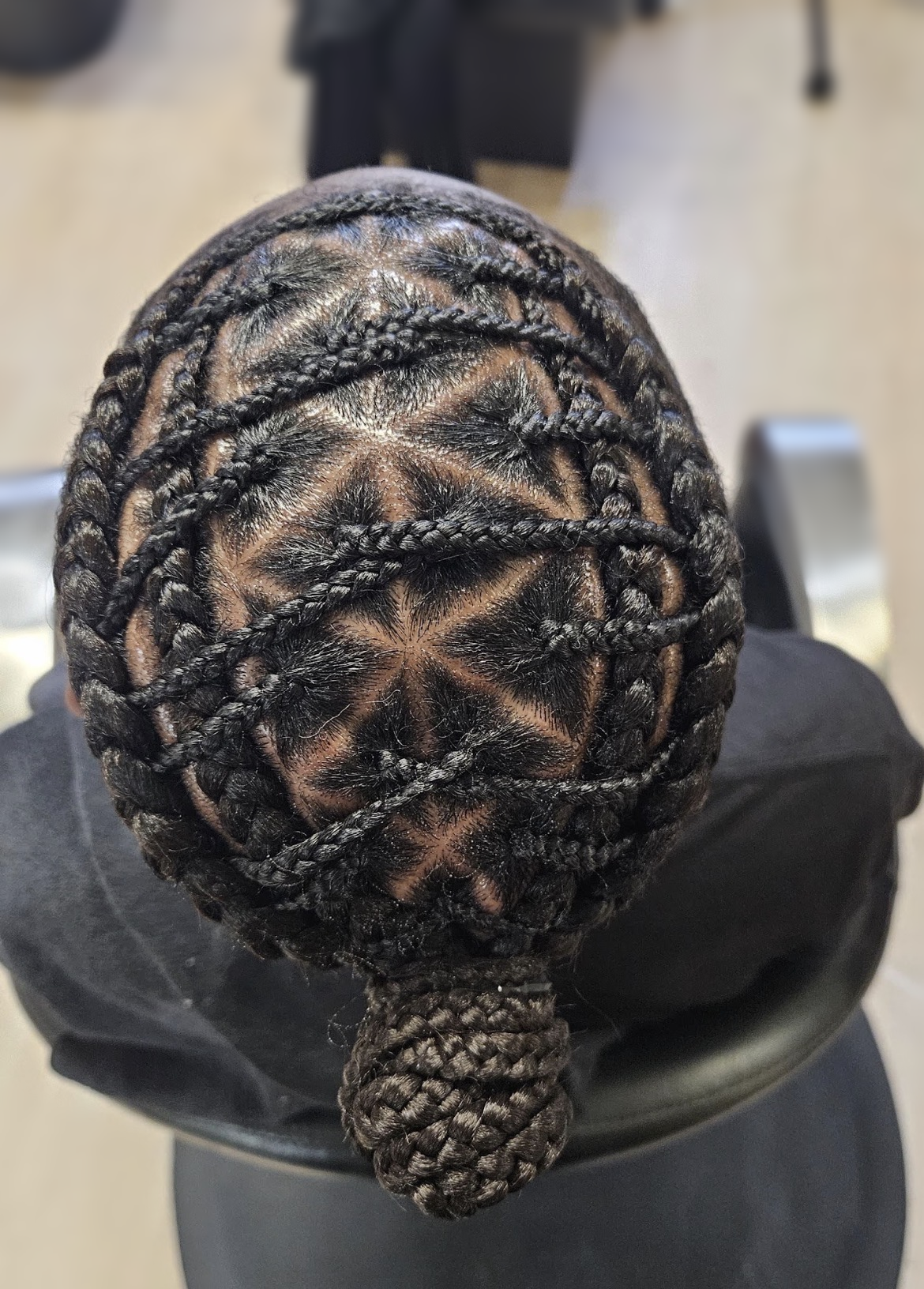Geometric cornrows with a low braided bun at TEXTURES Hair Salon