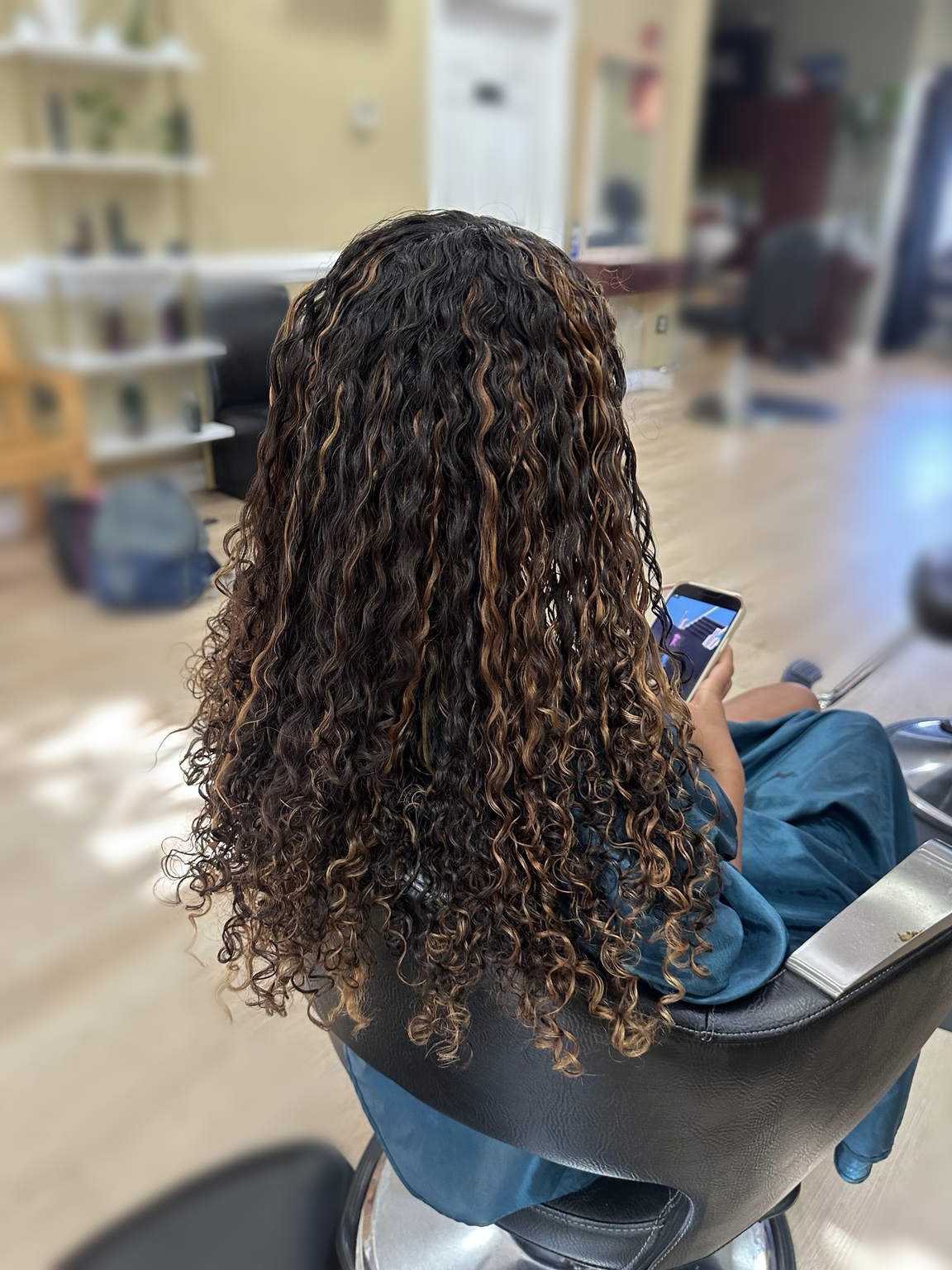 Long defined curls with warm highlights at TEXTURES Hair Salon